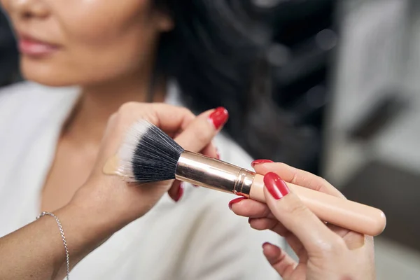 Detaljeret billede af blush børste i makeup kunstner arme i salon - Stock-foto
