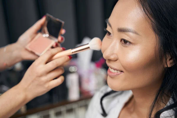 Jovem senhora elegante está recebendo visagem com cosméticos de luxo no espaço de beleza — Fotografia de Stock