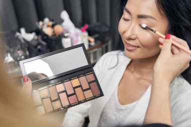 Tanımlanamayan makyaj sanatçısı kuaförde müşteri için yüz ifadesi yapıyor