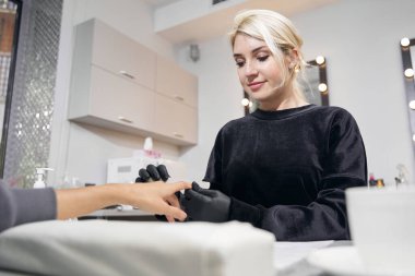 Manikürcüde tırnak törpüsüyle çalışan beyaz kadın üstat.