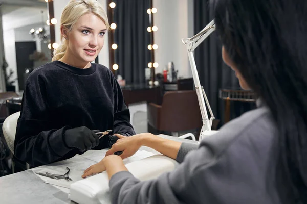 Feliz mestre atraente fazendo cuidados de manicure com equipamentos especiais no salão de beleza — Fotografia de Stock