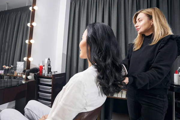 Profesyonel güzellik ustası salonda müşteriyle çalışıyor.