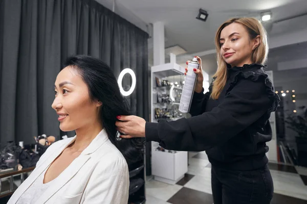 Krásná usměvavá asijská obchodní dáma dostává péči o vlasy v holičství shop — Stock fotografie