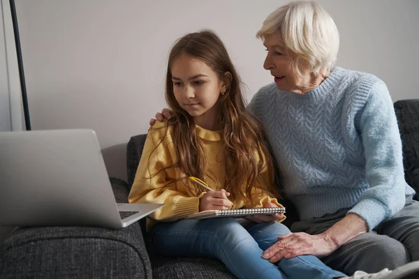 Прекрасный ребенок и ее бабушка смотрят на экран ноутбука — стоковое фото
