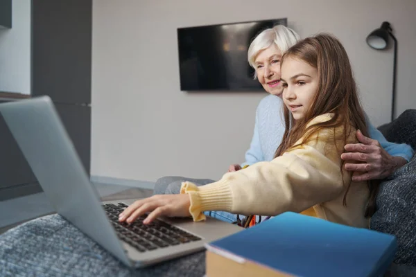 Умная девочка показывает своей бабушке, как пользоваться ноутбуком — стоковое фото
