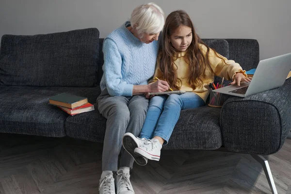 Заботливая бабушка помогает маленькой девочке с домашним заданием — стоковое фото