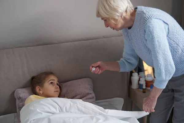 Niña en la cama atendida por su abuela cariñosa — Foto de Stock