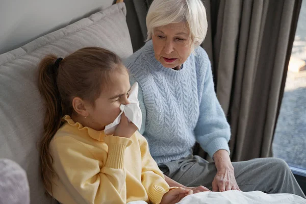 Abuela preocupada viendo a un niño enfermo estornudar en un pañuelo — Foto de Stock