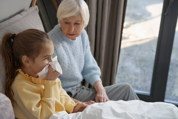 Preocupada abuela cuidando de un niño enfermo en la cama — Foto de Stock