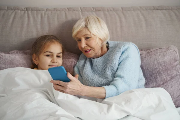 Бабушка выглядит удивлённой, когда пользуется смартфоном — стоковое фото