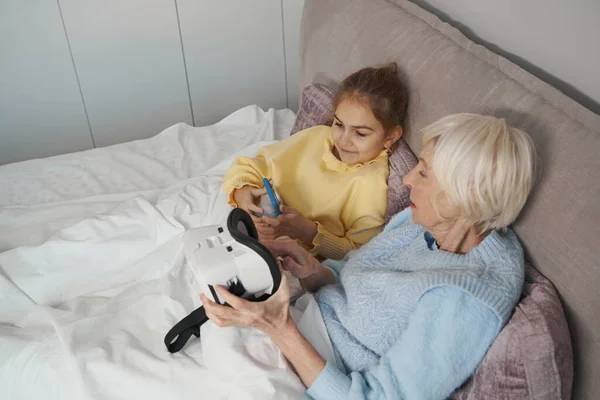 Señora mayor progresista y su nieta probando dispositivos de realidad virtual — Foto de Stock
