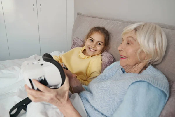 Chico emocionado viendo a su abuela probar los auriculares de realidad virtual — Foto de Stock