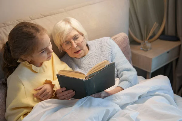 Linda chica y su abuela haciendo una rutina de cuentos para dormir — Foto de Stock