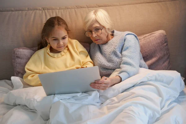 Пожилая женщина и ее внучка смотрят фильм на ноутбуке — стоковое фото