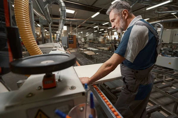 Senior bearded man looking at piece of plank — Foto Stock