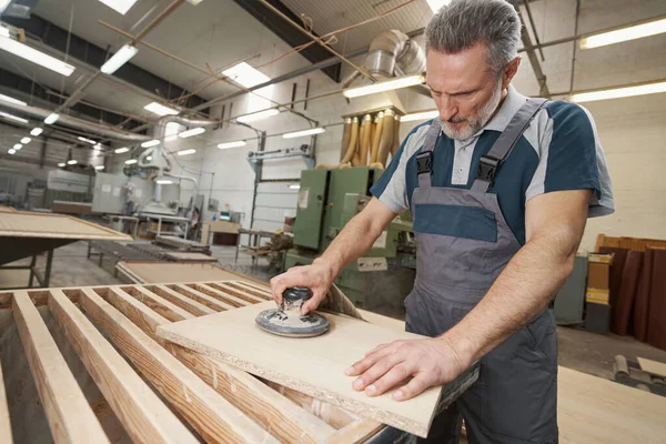 Serious male joiner polishing piece of veneer — Foto Stock