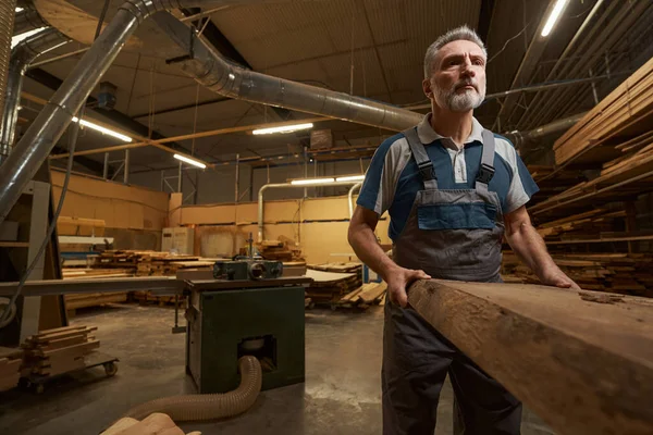 Concentrated male carpenter putting wood on machine — Foto Stock