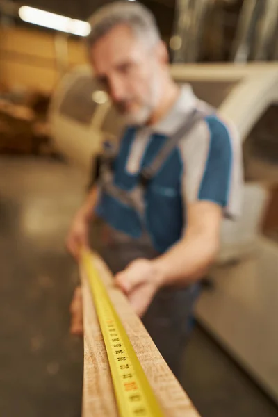 Silhouette of joiner using measuring tape for checking bar — Foto Stock