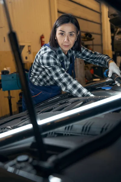 Well-trained female mechanic inspecting a car at workshop — Stockfoto