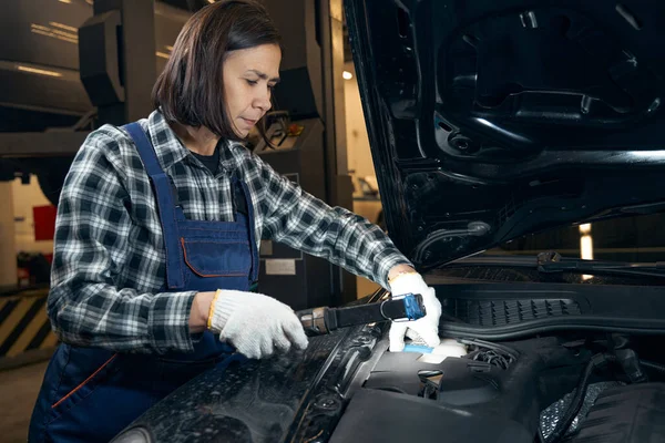 Skillful female mechanic doing car diagnostics at service station — Stock fotografie