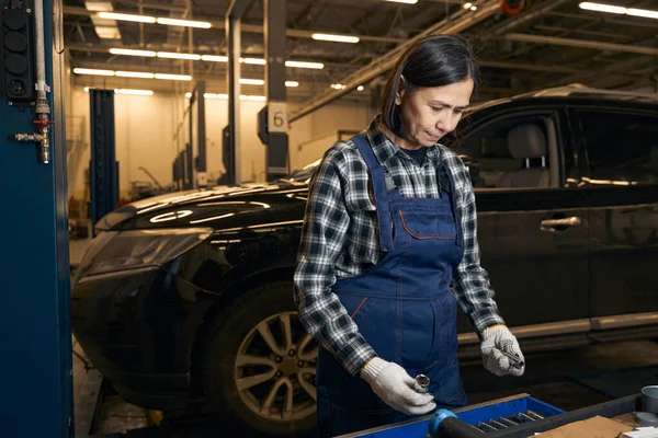 Serious female mechanic is holding different instruments — Stockfoto