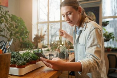 Atölyede çalışan ve telefona bakan bir kadın.