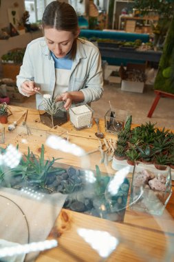 Stüdyoda çalışan ve çiçek eken bir kadın.