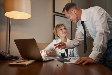 İş arkadaşları bir şeyler tartışıyor, otel odasında dizüstü bilgisayarla çalışıyorlar.