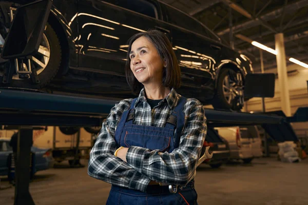Proud female mechanic happily posing at her workplace — Stockfoto