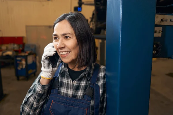 Excited female mechanic chatting on phone during break from work — Stockfoto