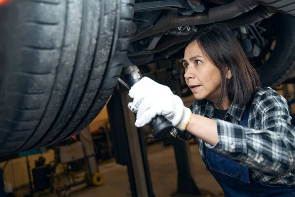 Worried-looking woman in technician uniform working at car service — Zdjęcie stockowe