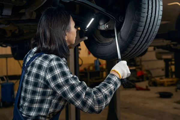Focused female car technician fixing a tyre — Fotografia de Stock