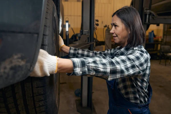 Hard-working female mechanic dealing with car wheels — Stockfoto