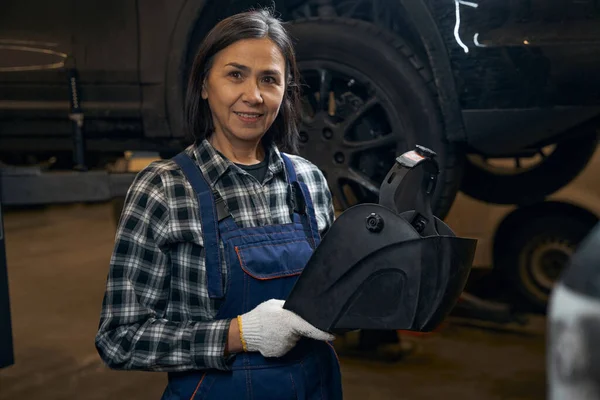 Friendly female mechanic standing at her workplace — Stockfoto