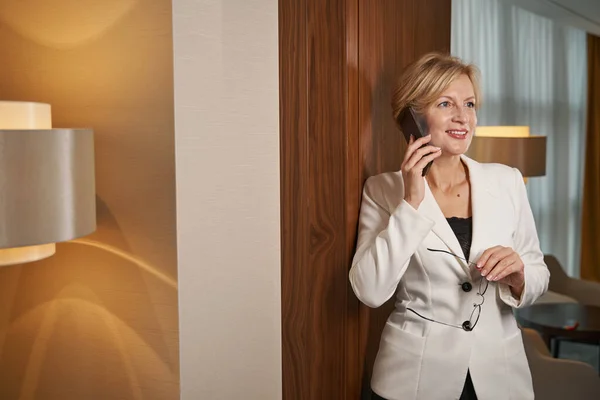 Businesswoman standing near the door in hotel, calling on phone — стоковое фото