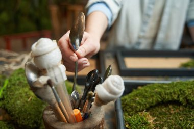 Ahşap kutudan aletlerle kaşık alan kadın.