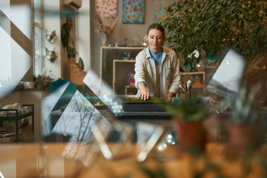Genç bir kadın yeşil malzemeyle film çekiyor.