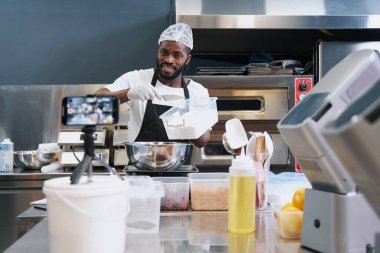 Gülümseyen şef internetten tatlı pişirme dersi çekiyor.