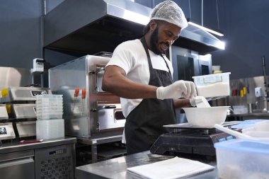 Şef pişirmeden önce malzemelerin ağırlığını ölçer.