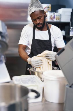 Mutfakta çalışan koruyucu elbiseli bir adam.