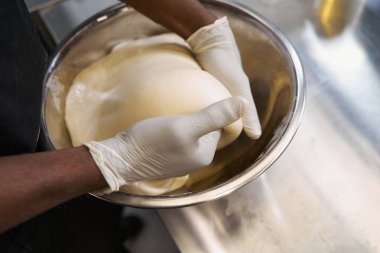 Koruyucu elbiseli bir adam mutfakta yemek pişiriyor.