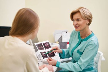 Genç ziyaretçisine bakan neşeli sarışın doktor.