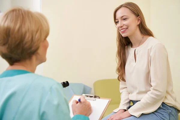Positiv kvinnlig patient som lyssnar på sin utövare — Stockfoto