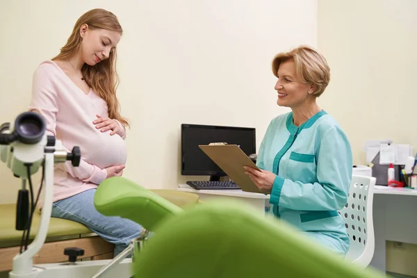 快乐成熟的医务工作者咨询她的孕妇 — 图库照片
