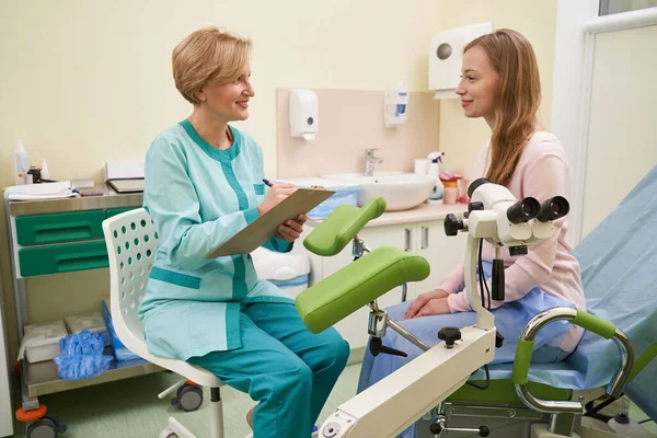 Potěšená mladá pacientka poslouchá svého lékaře — Stock fotografie