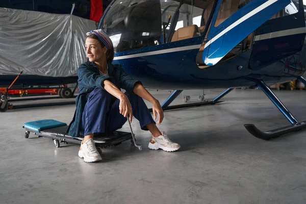 Trött elegant kvinnlig ingenjör vilar efter arbetet med flygplan i hangar — Stockfoto