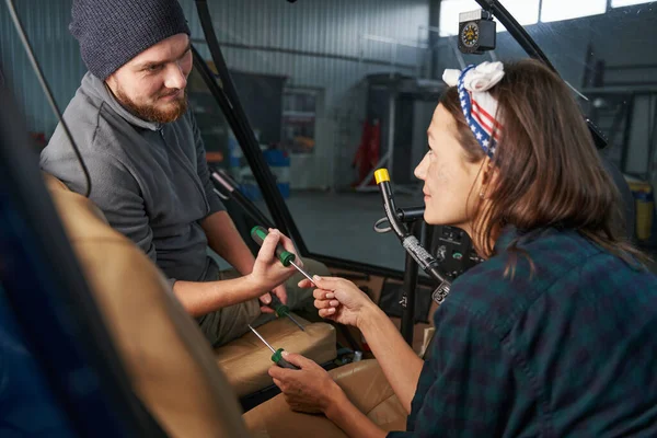 Knappe man ingenieur en mooie vrouw met schroevendraaier in handen in hangar — Stockfoto