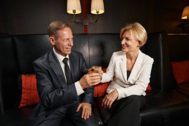 Yoğun bir iş gününden sonra iş ortağıyla rahatlayan gülümseyen kadın.