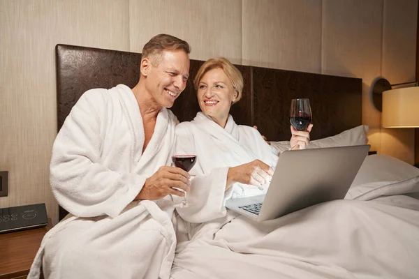 Senhora alegre e homem satisfeito desfrutando de relaxamento na cama no hotel — Fotografia de Stock