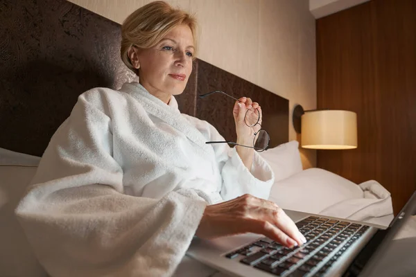 Exitosa mujer de negocios trabajando remotamente desde su cómoda cama de hotel — Foto de Stock